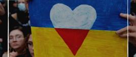Ukraińska flaga na tle flagi Polski. Flaga Polski ma kształt serca. Jest też napis Pomagamy Ukrainie. 