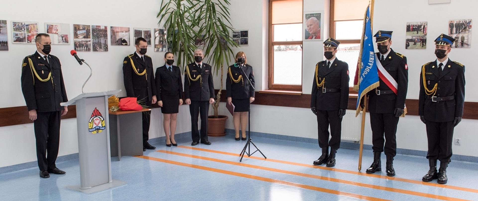 Na fotografii komendant Komendy Powiatowej Państwowej Straży Pożarnej w Sokołowie Podlaski starszy brygadier Tomasz Wilk, strażacy jednostki w galowym umundurowaniu oraz poczet ze sztandarem jednostki złożony z trzech osób. 