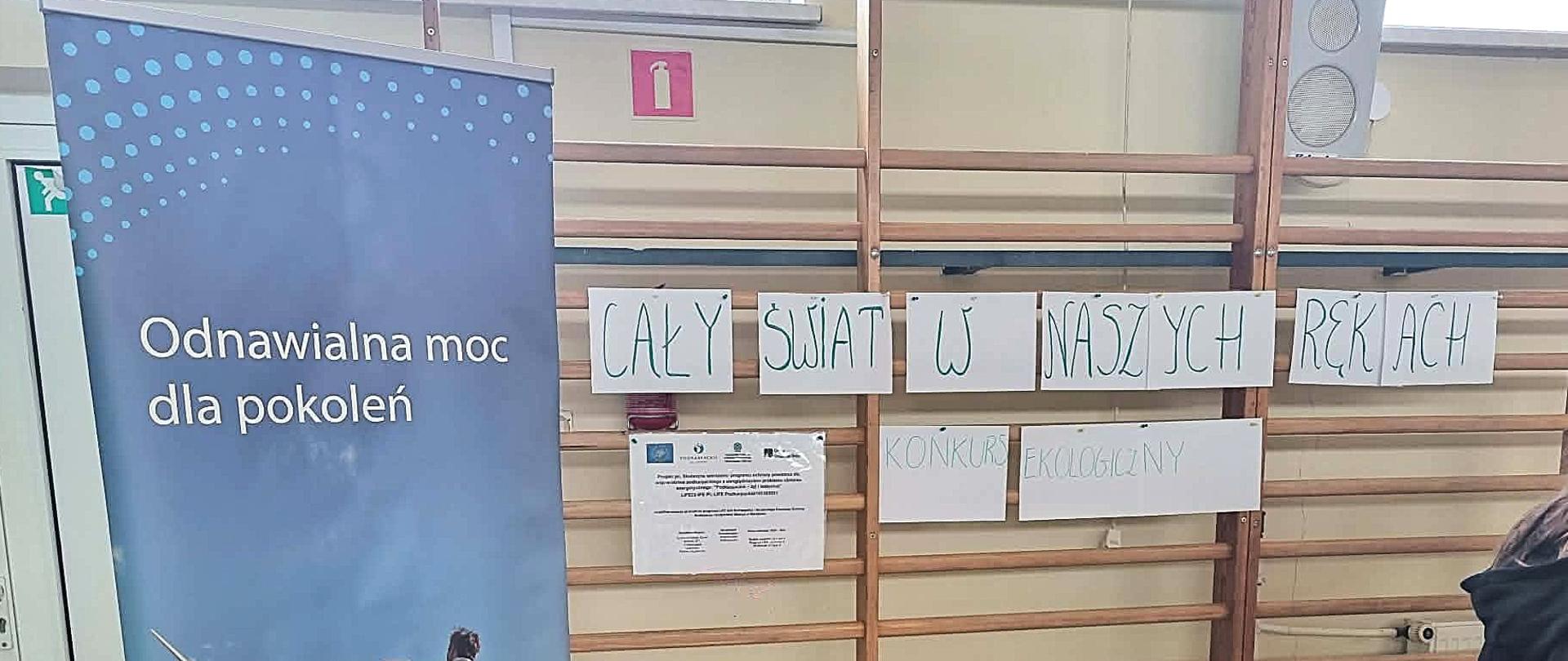 Zdjęcie przedstawia napis dot. konkursu ekologicznego "Cały świat w naszych rękach", po lewej baner