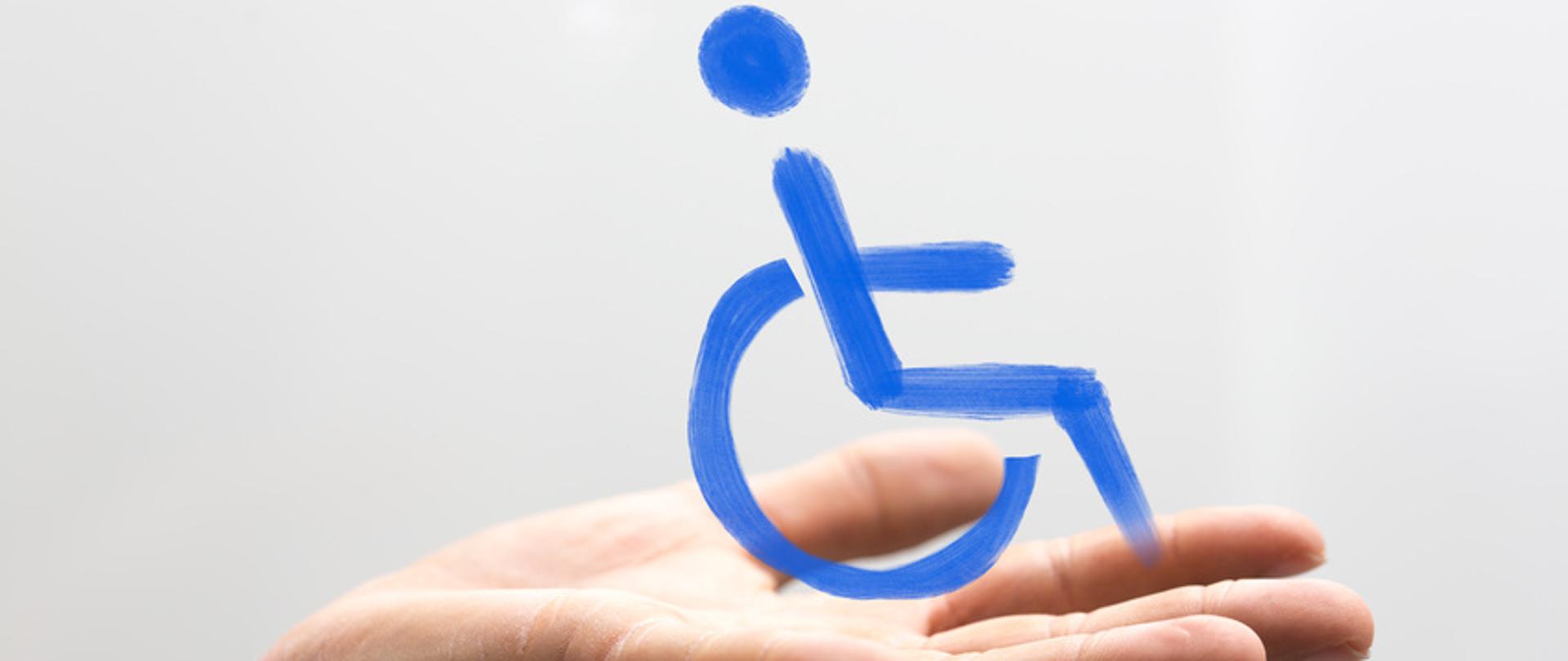 ręka trzymająca wózek z osobą niepełnosprawną
