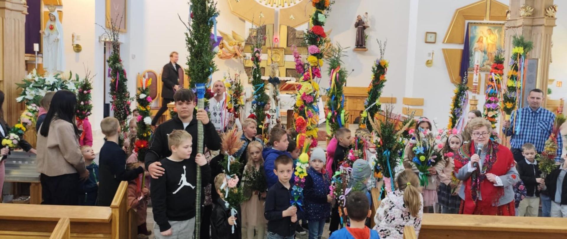 Dzieci z palmami stoją przed ołtarzem w kościele w Sieniawie 