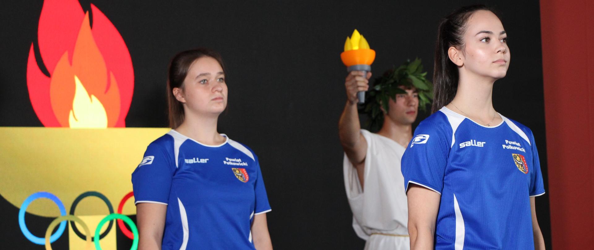 uczniowie odpalają symboliczny znicz olimpijski i niosą flagę Polski 