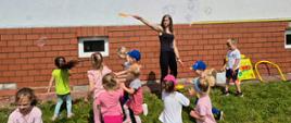 Pani nauczycielka puszcza dla dzieci bańki mydlane