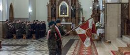 Na zdjęciu uczniowie klas mundurowych ZS nr 1 w Sokołowie Podlaskim prezentujący w kierunku ołtarza sztandar Światowego Związku Żołnierzy Armii Krajowej – Koła w Sokołowie Podlaskim. W tle nawa boczna oraz stojący w mundurach uczniowie.