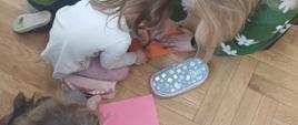 Zdjęcie przedstawia przedszkolaków wraz z wychowawcą podczas tworzenia "łapek" z kolorowego papieru. 