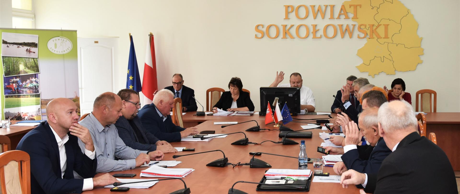 Na zdjęciu widoczni Radni rady powiatu sokołowskiego siedzący przy stole obrad podczas głosowania 
