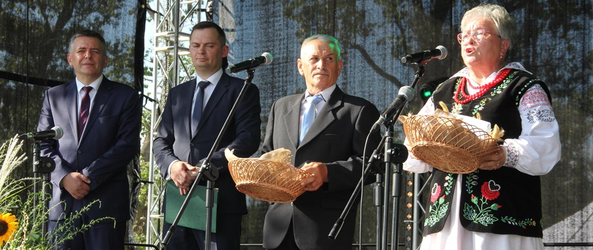 Na scenie stoją starostowie dożynek z chlebem, a po ich prawej stronie starosta oleśnicki i wójt Dobroszyc