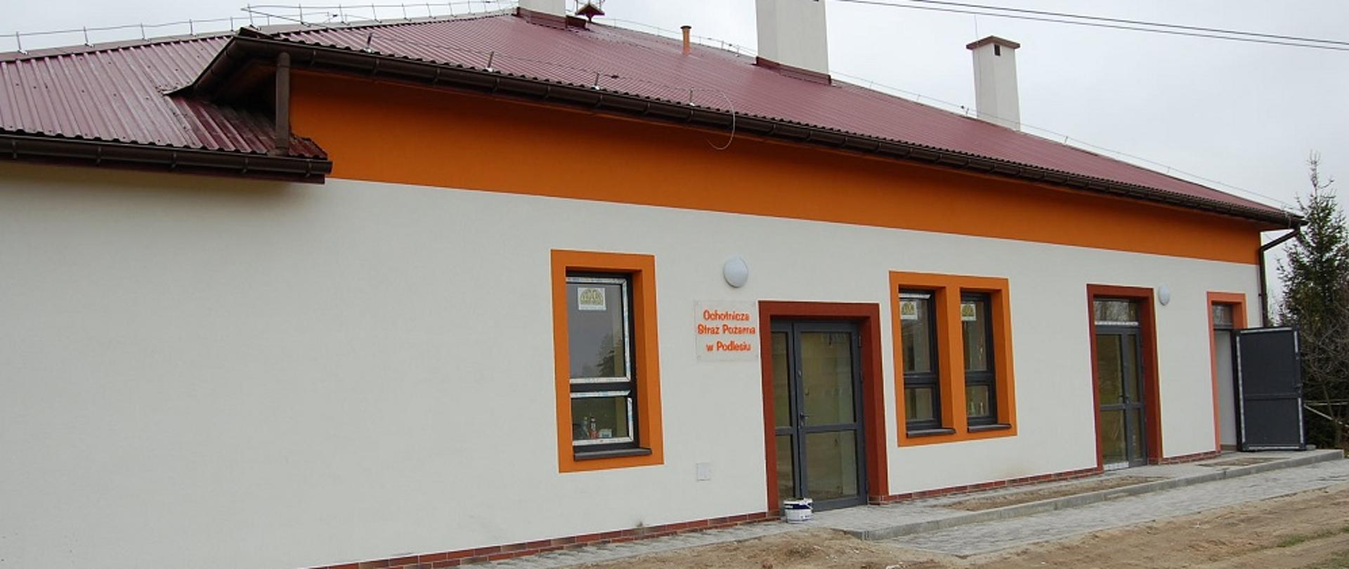 Jasno, pomarańczowy budynek z czerwonym dachem. 