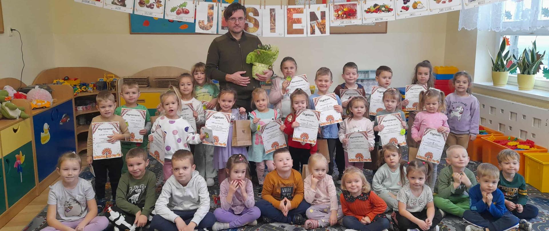 Grupowe zdjęcie przedszkolaków z panem leśniczym