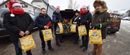 Starosta wraz z wolontariuszami stoją przed samochodem pełnym paczek z jedzeniem