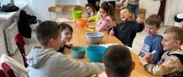 Dzieci siedzą przy ławkach szkolnych i przygotowują zdrowie posiłki z owoców