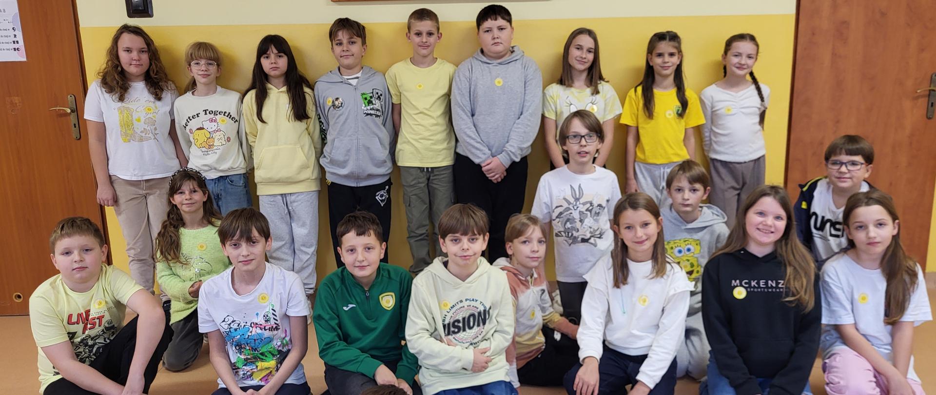Grupa uczniów pozuje do zdjęcia na żółtym korytarzu