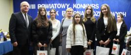 Zdjęcie przedstawia laureatów konkursu, którzy trzymają w dłoniach nagrody (6 osób). Od lewej strony Pan Robert Maciej Rosiak Wicestarosta Zambrowski, w środku kobieta ubrana w kostium w kolorze szarym.