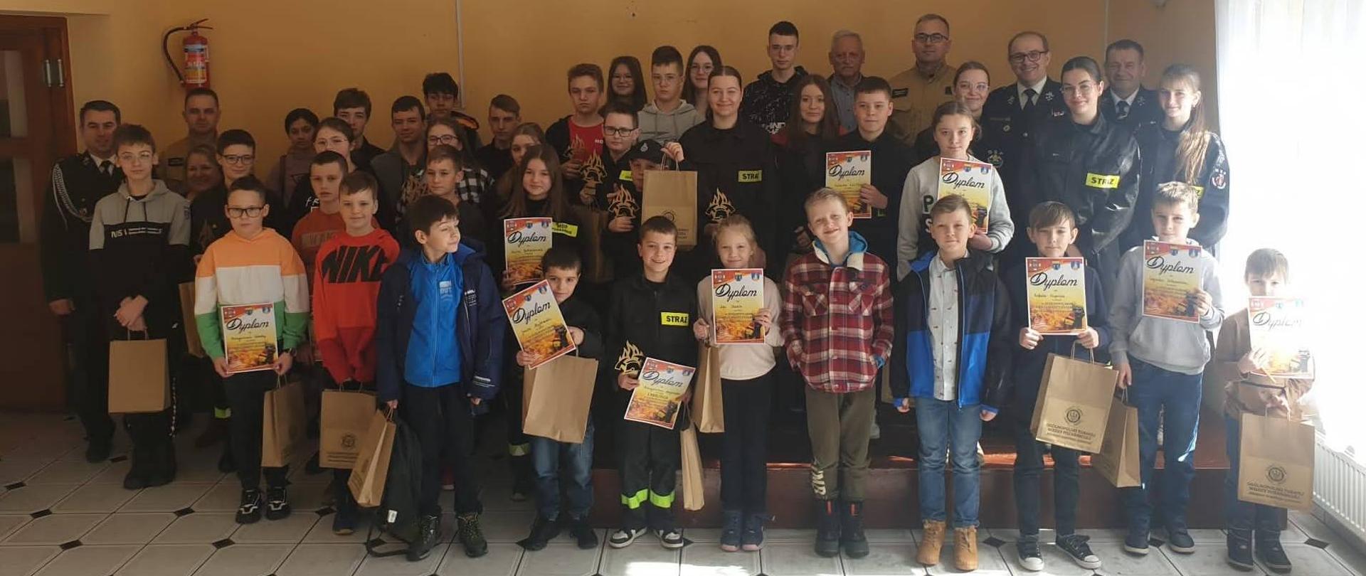 Grupa uczestników pozuje do wspólnego zdjęcia trzymając dyplomy w ręku