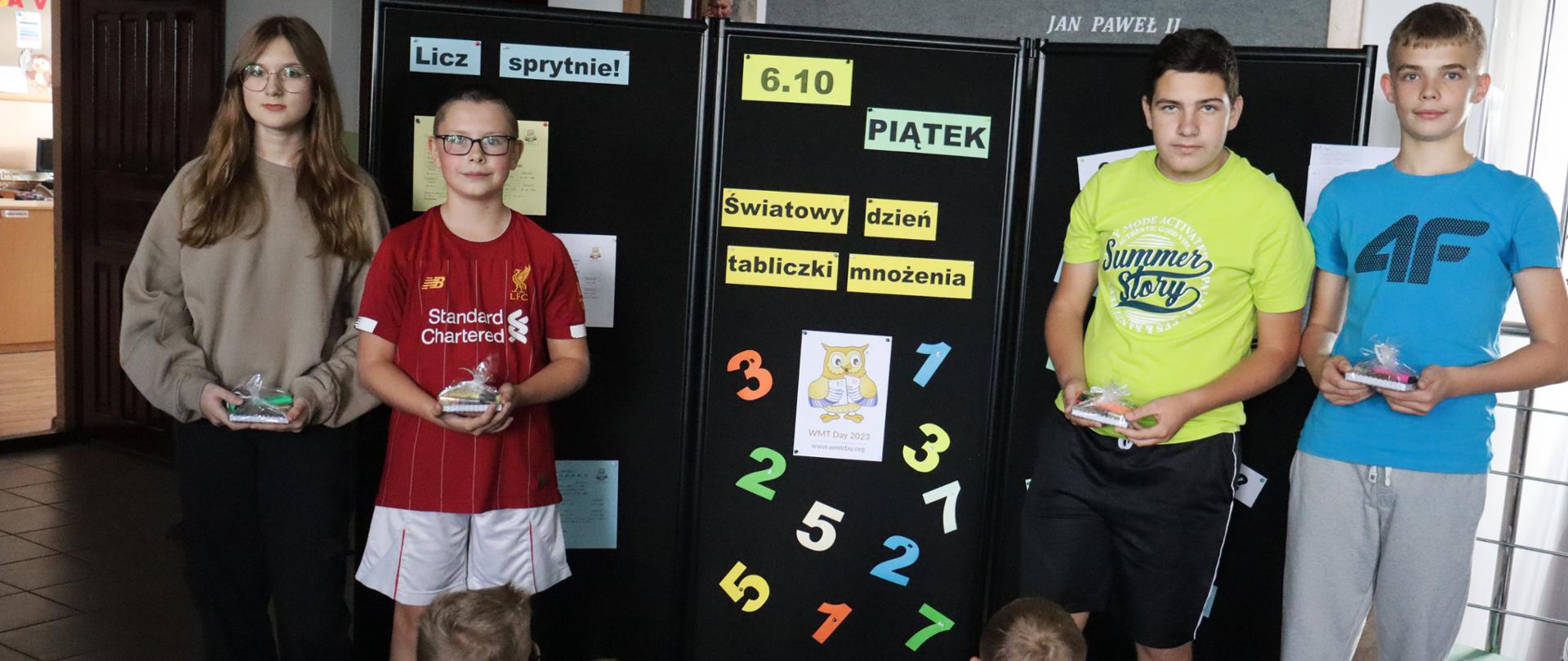 Uczniowie stoją na tle tablicy z napisem Światowy Dzień Tabliczki Mnożenia