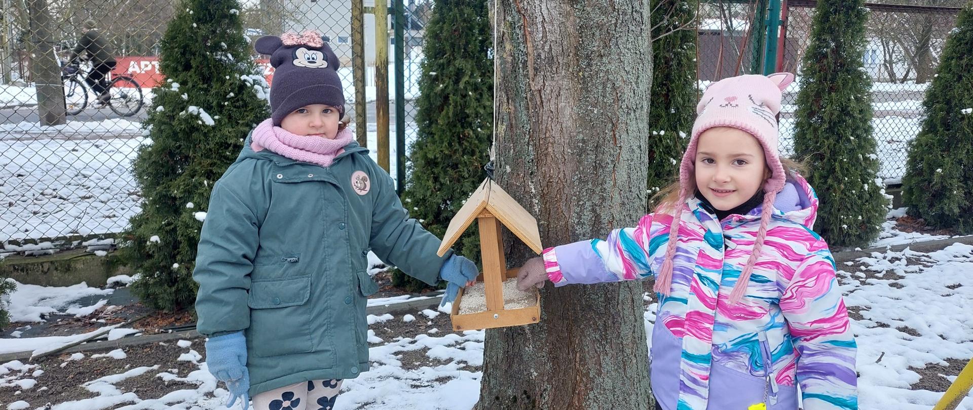 2 dzieci przy karmiku dla ptaków 