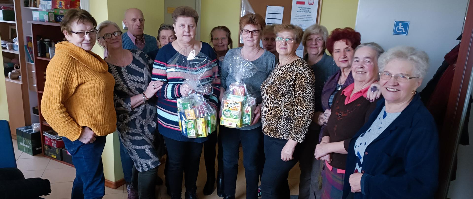Zdjęcie grupowe członków klubu "Senior+" z prezentami w postaci herbat