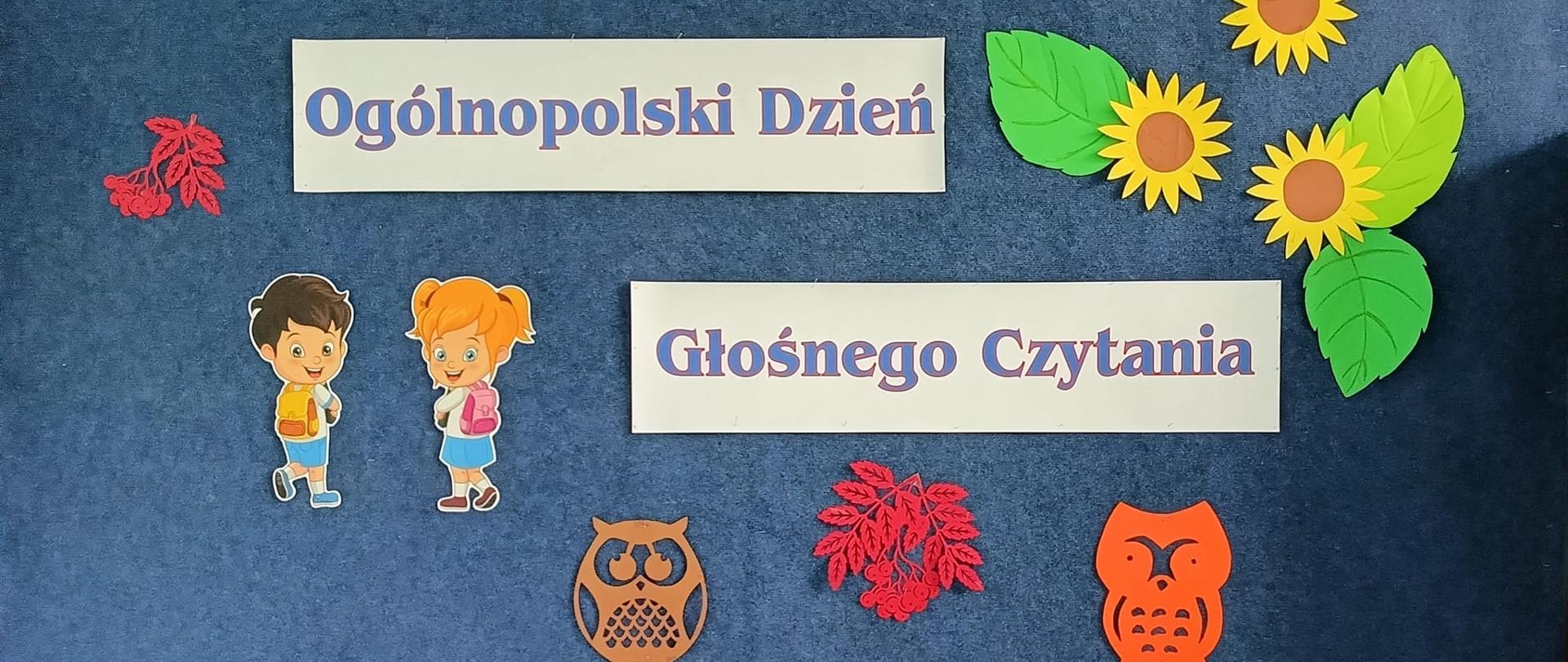 U dołu strony na stoliku wystawka książek, Tło zdjęcia w kolorze granatowym z napisem, przypiętymi słonecznikami i postaciami .
