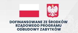 Tablica promocyjna w kolorze szarości na której widnieją granatowe napisy zgodne z treścią artykułu. Na tablicy na górze po środku widzimy od lewej polską flagę oraz polskie godło. Poniżej napis: "dofinansowane ze środków rządowego programu odbudowy zabytków. Poniżej nazwa zadania wskazana w artykule oraz kwoty.