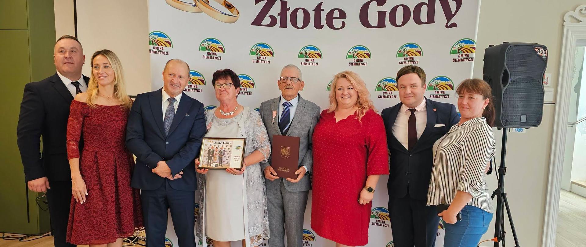 Grupa osób pozuje razem przed transparentem z napisem „Złote Gody”.