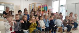 Dzieci siedzą na ławkach, biją brawo - w trakcie uroczystego podsumowania konkursu
