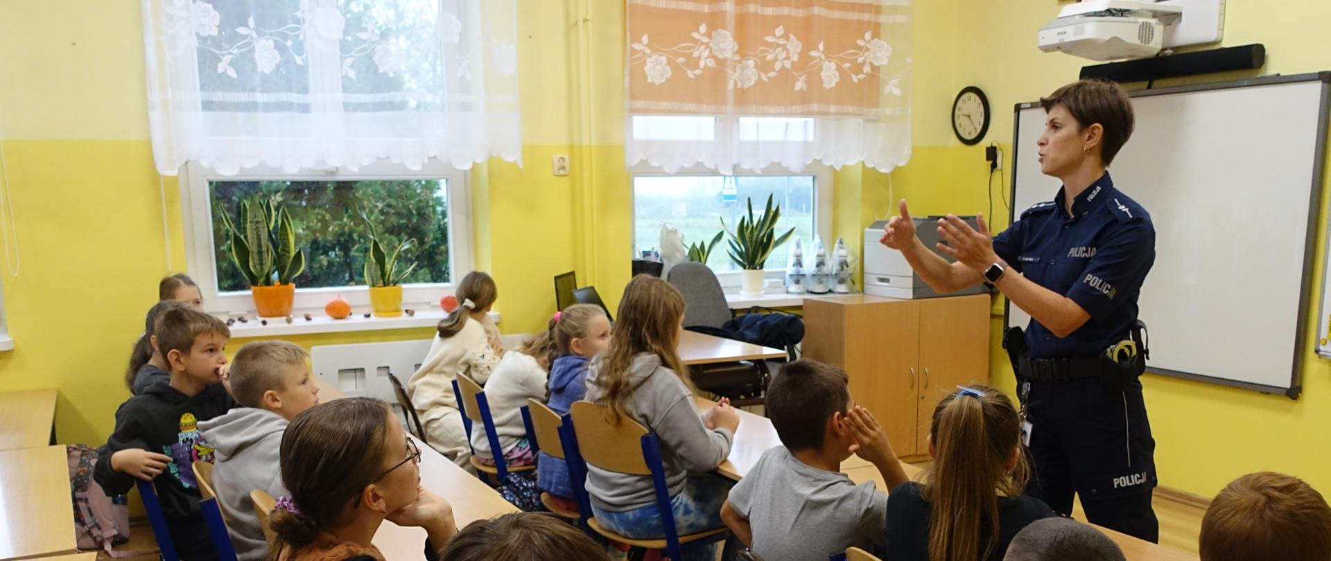 Uczniowie klas młodszych słuchają prelekcji policjantki