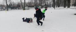 Zabawy na śniegu - dzieci pokonują tor przeszkód w zaprzęgu