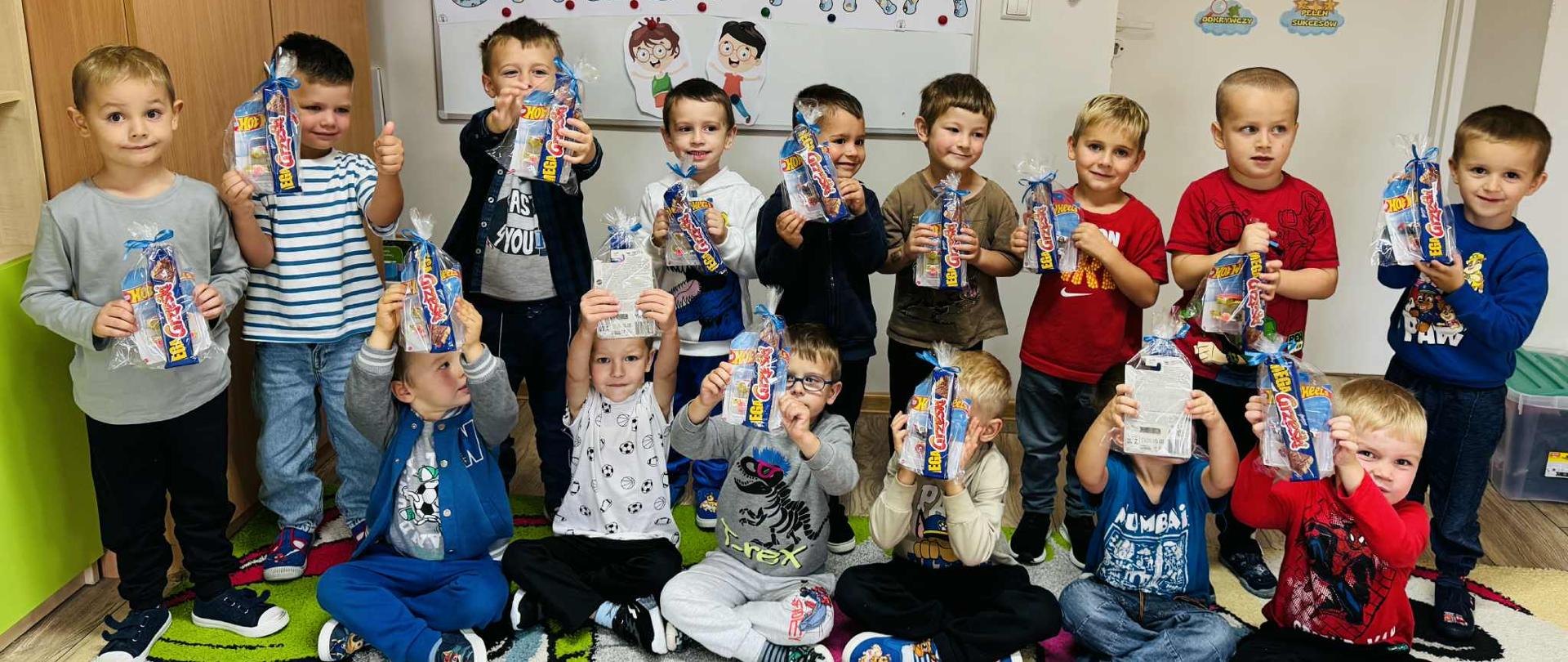 Grupa dzieci pozuje z prezentami z okazji Dnia Chłopaka