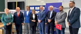 Grupa osób stoi ubrana elegancko w klasie 