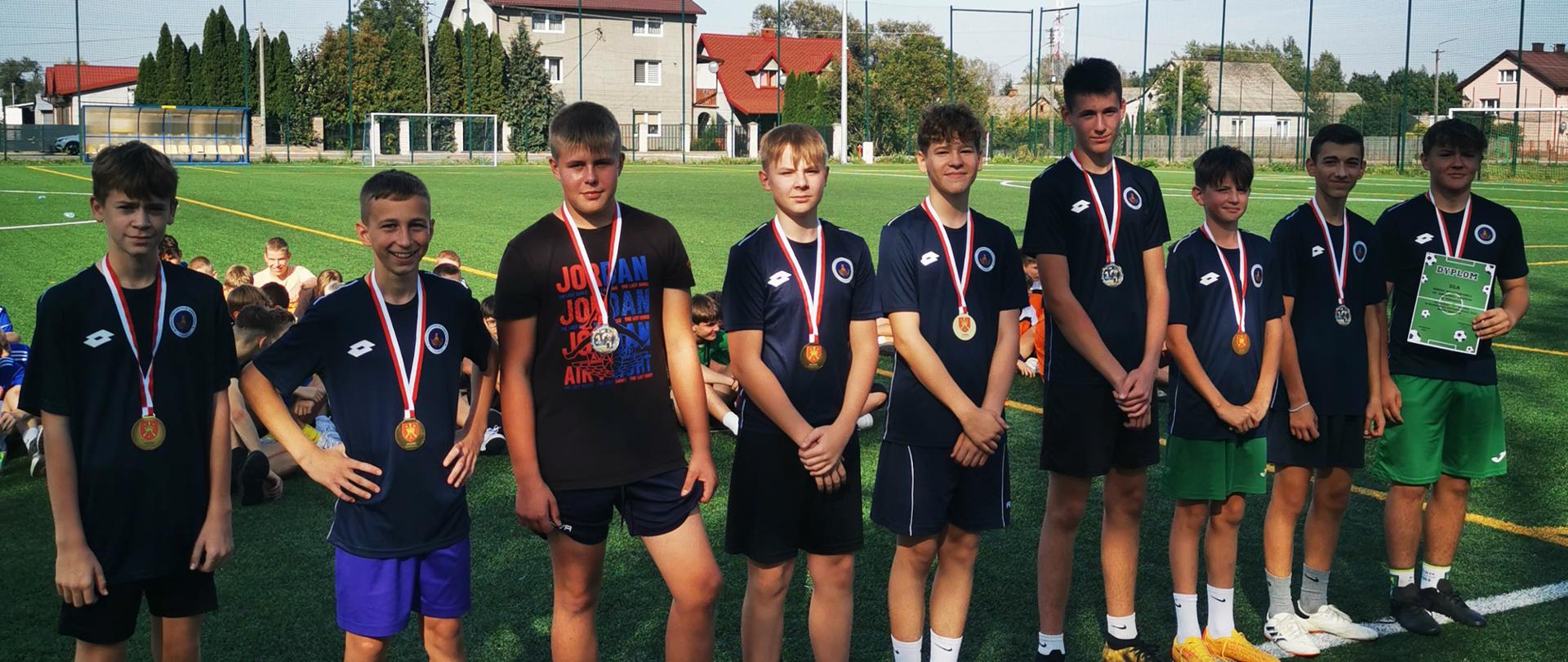 Grupa chłopców w spodenkach i koszulkach z medalami na szyi