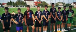Grupa chłopców w spodenkach i koszulkach z medalami na szyi