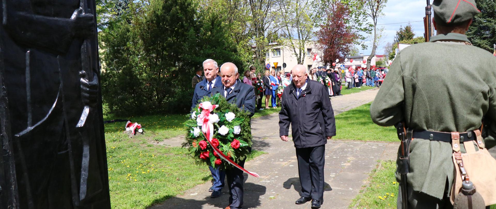 Przewodniczący Rady Miejskiej, Burmistrz Miasta i Gminy Budzyń oraz jego Zastępca składający wiązankę kwiatów pod Pomnikiem Pamięci Narodowej.