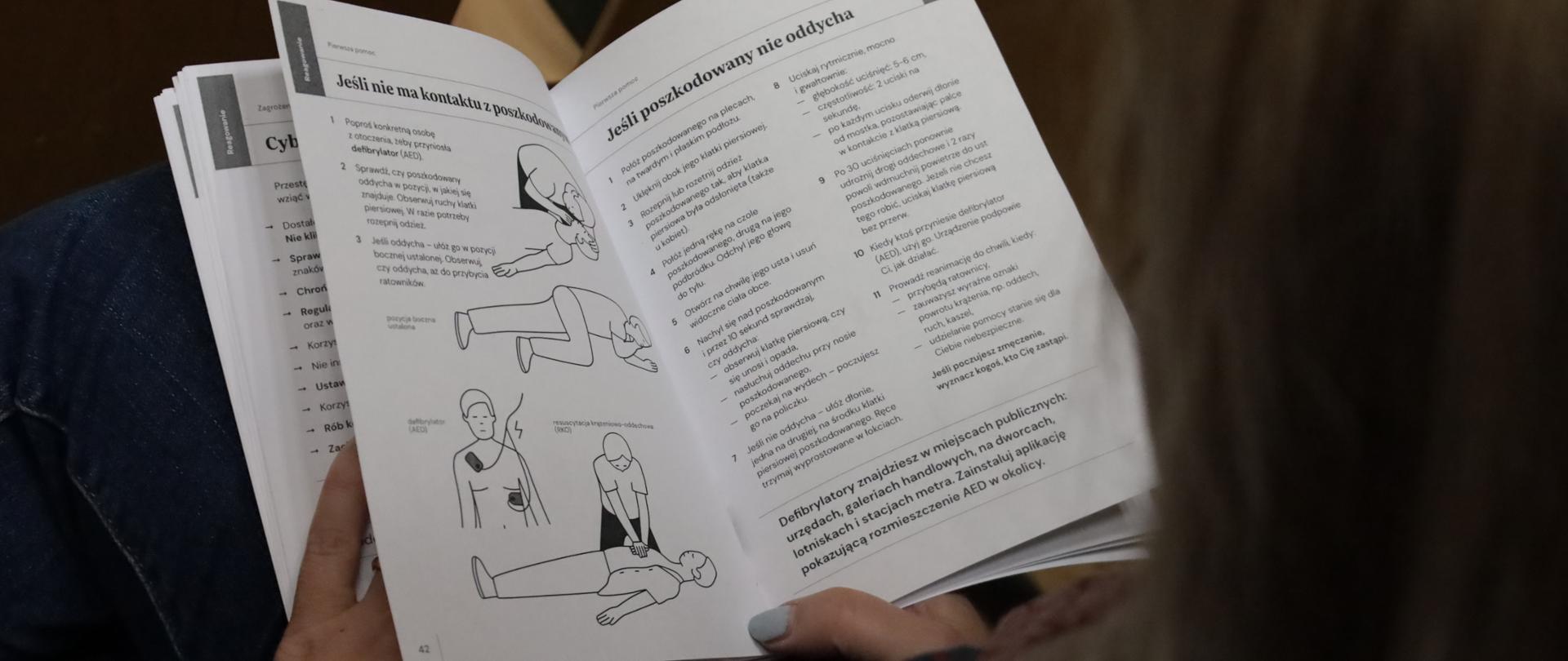 Uczestniczka przegląda poradnik dot. bezpieczeństwa