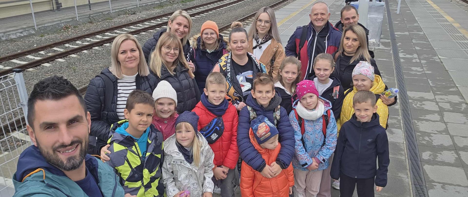 Dzieci i rodzice stoją na stacji PKP w Mielcu i czekają na pociąg do Krakowa