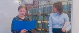Emilia Jabłońska i Łucja Gąska prezentują swój lapbook na konkursie czytelniczym.