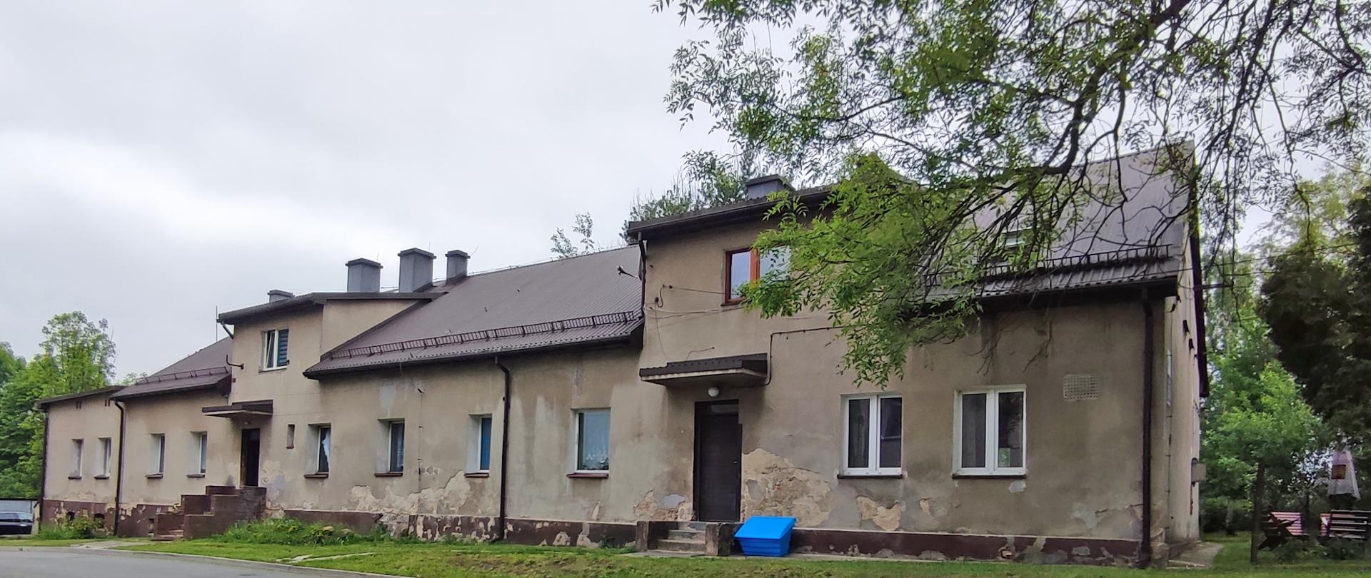 Budynek ze zniszczoną szarą elewacją