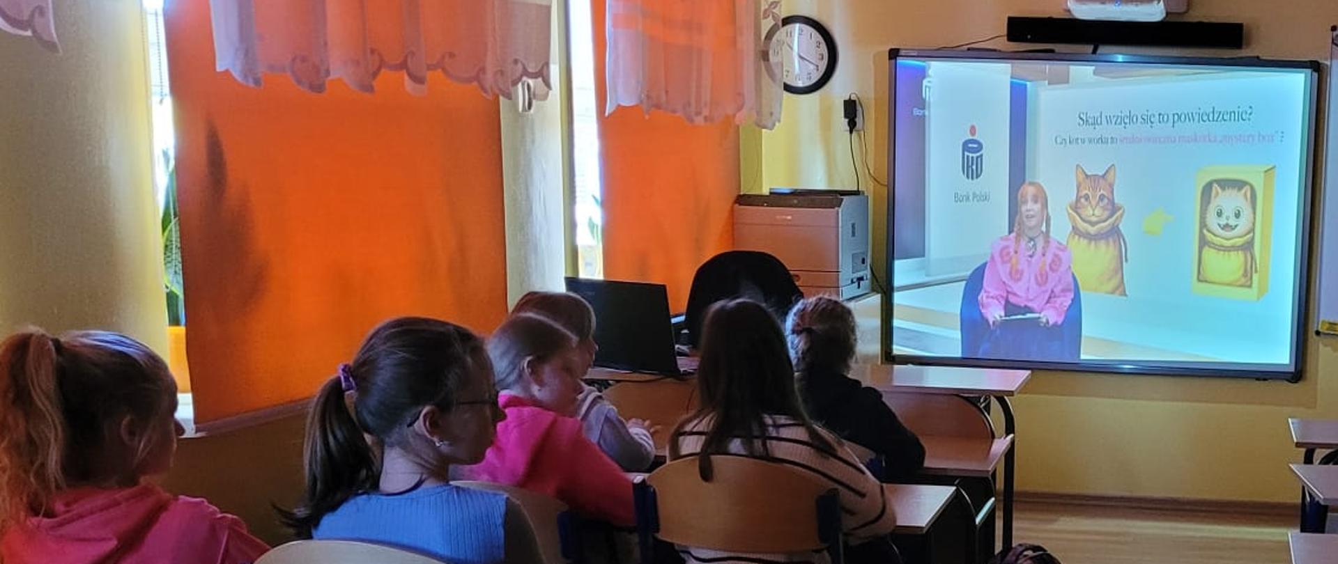 Uczniowie klasy IV siedzą w ławkach - uczestniczą w lekcji online