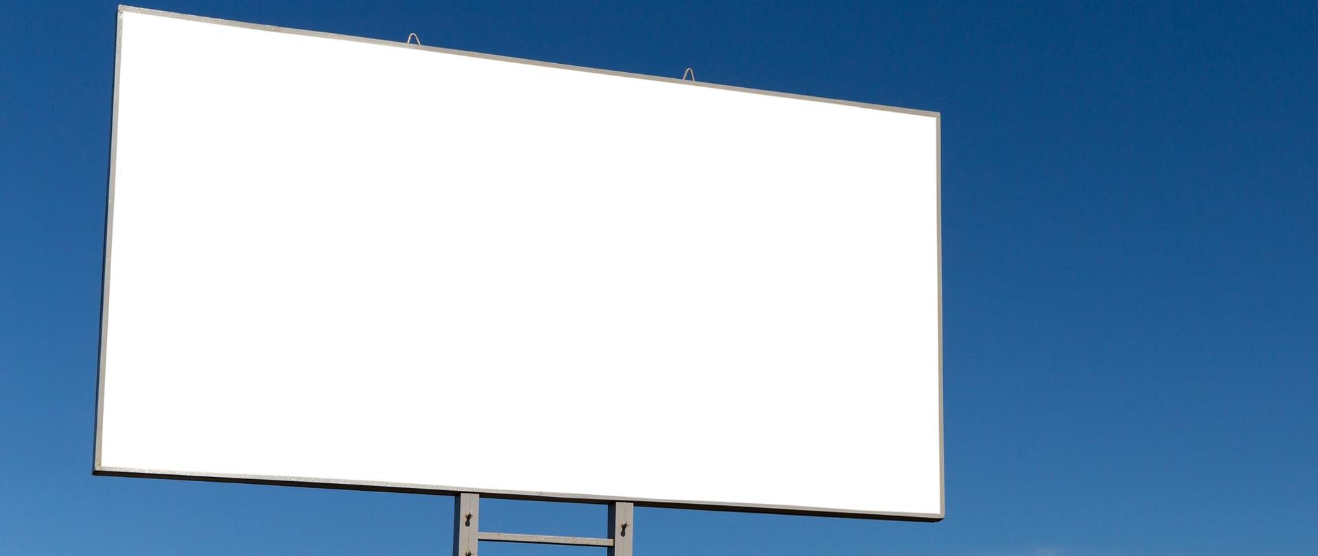 Zdjęcie przedstawia billboard bez żadnego napisu ustawiony na tle niebieskiego nieba na zewnątrz