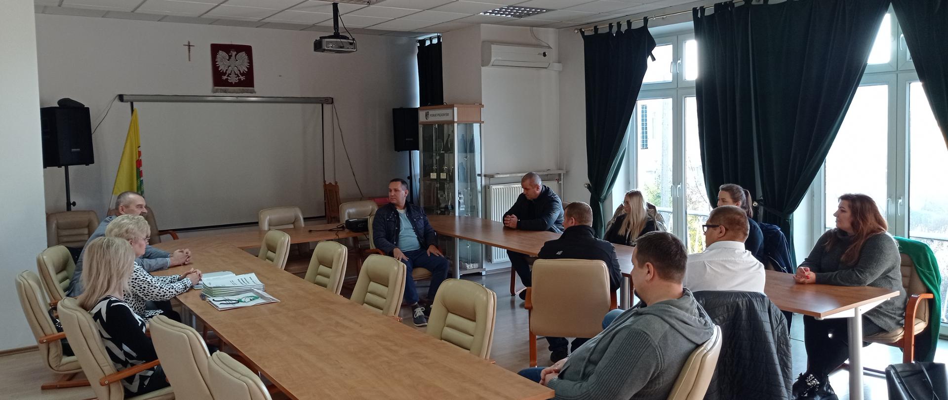 Zdjęcie przedstawia Ośmiu nowych przedsiębiorców powiatu przasnyskiego w dniu podpisania umów na otrzymanie wsparcia finansowego. Przedsiębiorcy - po prawej, Wicestarosta Powiatu Przasnyskiego Waldemar Trochimiuk, Zastępca Dyrektora Powiatowego Urzędu Pracy w Przasnyszu – Anna Obrębska oraz pracownik PUP – Barbara Garlińska - po lewej. Zdjęcie wykonano w sali konferencyjnej w siedzibie Powiatu Przasnyskiego.