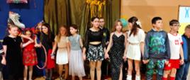 Dziewczynki i chłopcy tańczą w kole trzymając się za ręce, ubrani są w karnawałowe stroje