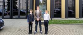 3 uczniów stoi przed budynkiem Akademii Nauk Stosowanych w Nowym Sączu, w której odbywa się rozdanie nagród