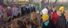 Dzieci stoją na około pomnika z dużej kamiennej płyty