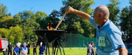 Pan Henryk Pieper zapala za pomocą pochodni znicz olimpijski