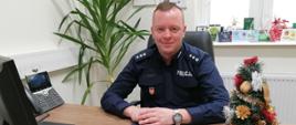 zdjęcie przedstawia siedzącego za biurkiem Komendanta Komisariatu Policji w Żabnie