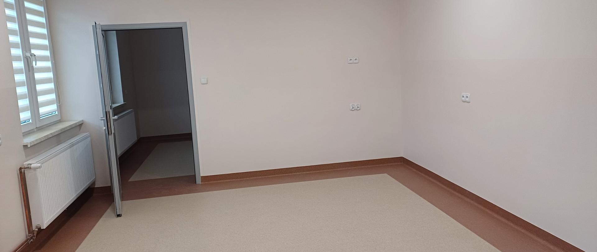 Zdjęcie przestawia puste pomieszczenie z lewej strony znajdują się drzwi do następnego pomieszczenia