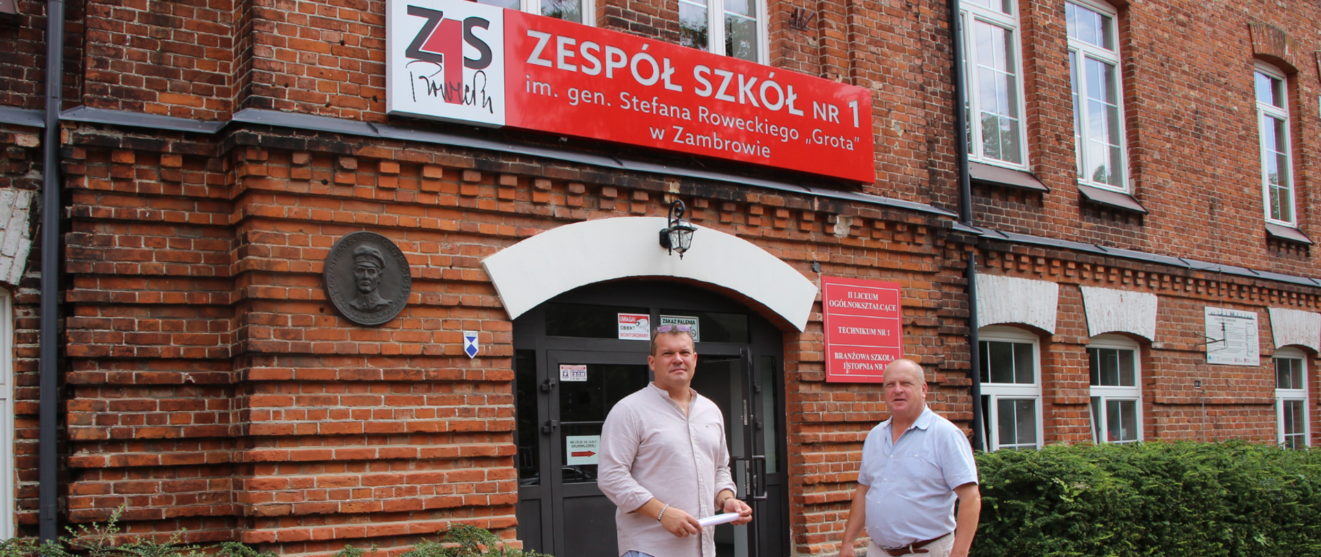 na zdjęciu wicestarosta zambrowski i dyrektor szkoły stoją przed budynkiem ZS1, którzy będą sprawdzać postępy i efekty prowadzonych robót