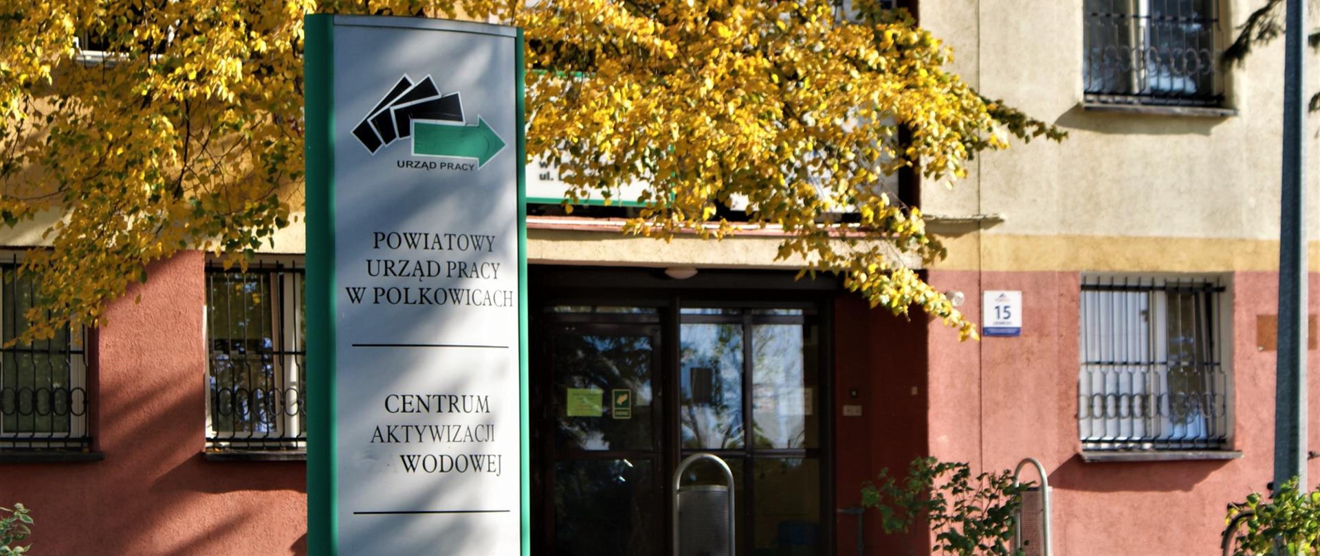 Tablica informacyjna oraz wejście główne do budynku Powiatowego Urzędu Pracy w Polkowicach.