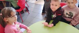 Dzieci siedząc przy stole, pozują do zdjęcia