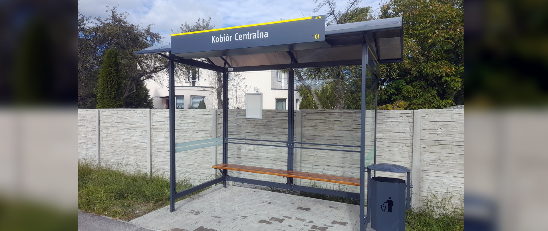 Grafitowa wiata przystankowa w tle betonowe ogrodzenie
