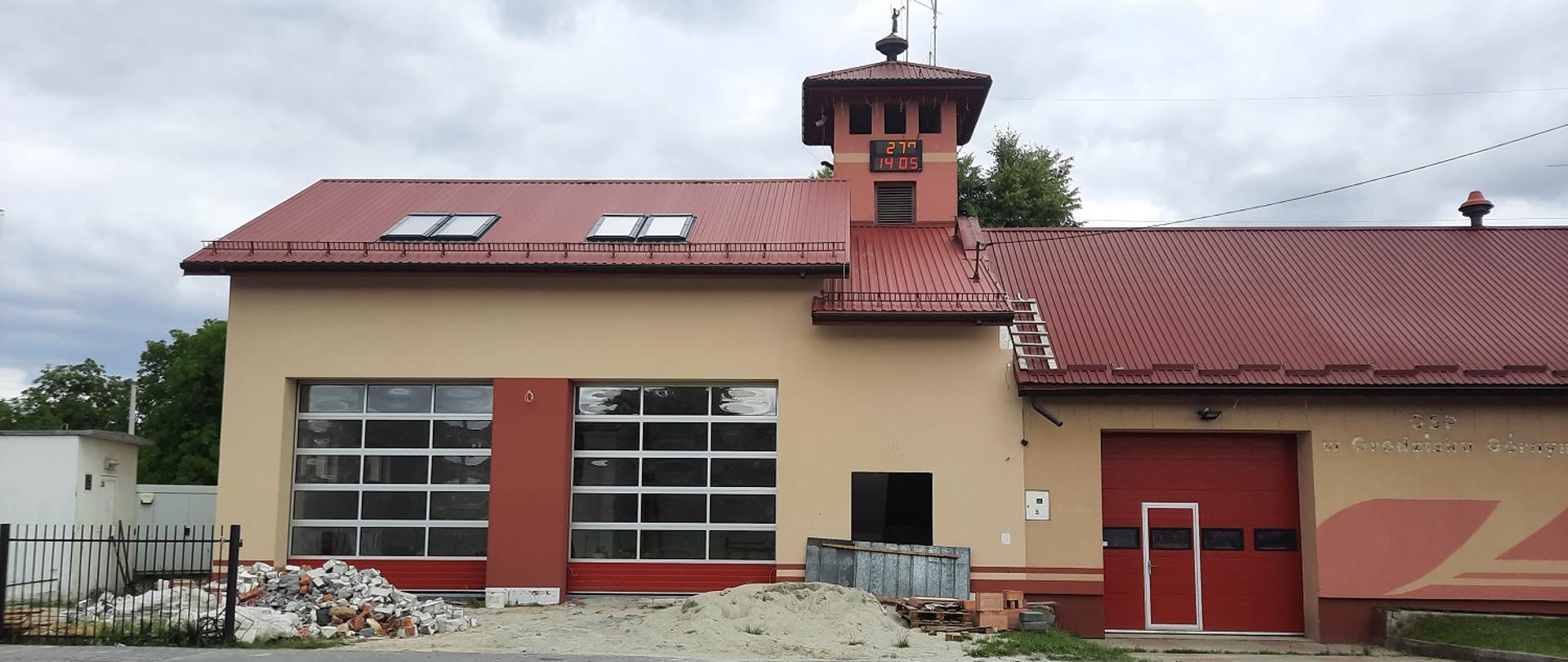 beżowo czerwony budynek remizy z dwiema dużymi bramami wjazdowymi,